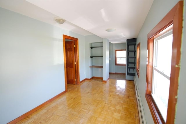 empty room with built in features, baseboards, and a baseboard heating unit
