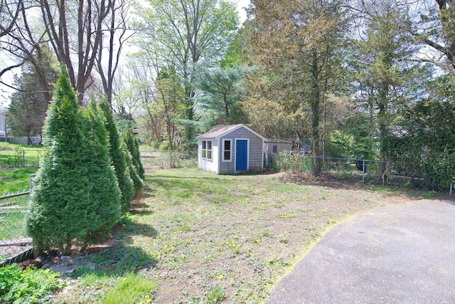 view of yard featuring an outdoor structure, a fenced backyard, and a storage shed