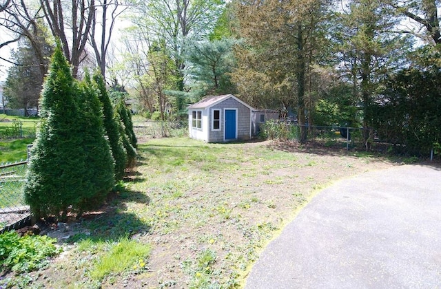 view of yard with an outdoor structure, a fenced backyard, and a shed