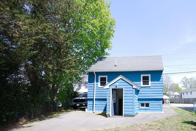 view of front of house featuring a shingled roof and fence
