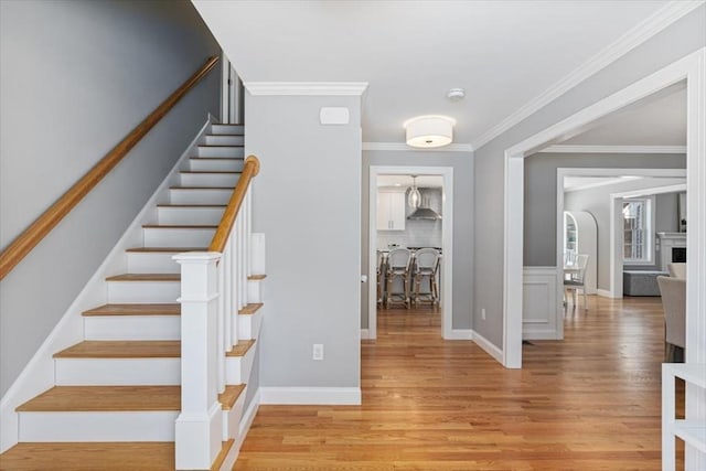 staircase with wood-type flooring and crown molding