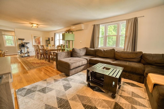 living room featuring light wood-type flooring, baseboard heating, and an AC wall unit