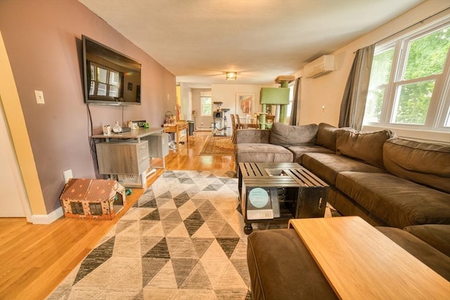 living room with light wood-style flooring, baseboards, a wealth of natural light, and a wall mounted AC