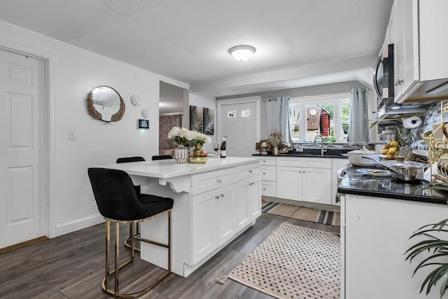 631 Chestnut St, Athol, MA 01331 - kitchen with stainless steel microwave, white cabinetry, dark wood-type flooring, a kitchen bar, and a center island