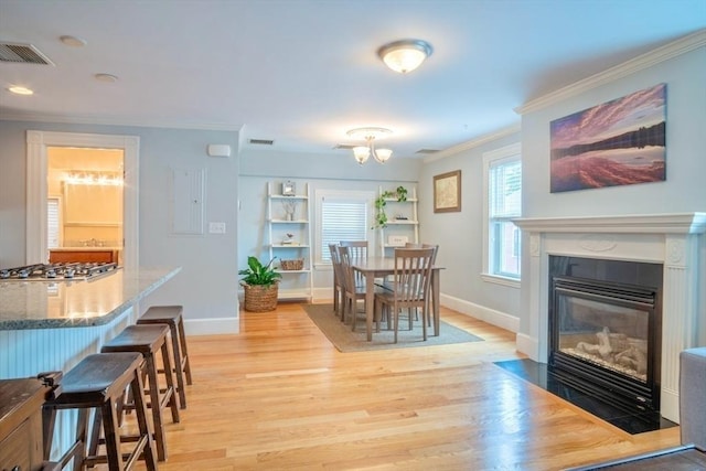 29 Carlton St Unit 2, Salem, MA 01970 - dining space with ornamental molding, light wood-type flooring, a chandelier, and a fireplace with flush hearth