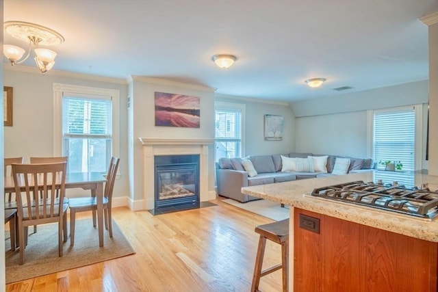 29 Carlton St Unit 2, Salem, MA 01970 - kitchen featuring stainless steel gas cooktop, healthy amount of natural light, ornamental molding, light wood-type flooring, and a fireplace with flush hearth