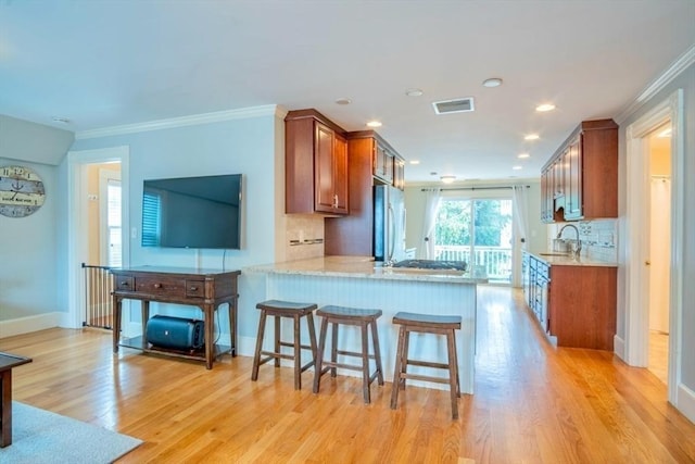 29 Carlton St Unit 2, Salem, MA 01970 - kitchen with freestanding refrigerator, brown cabinetry, light wood finished floors, backsplash, and a peninsula