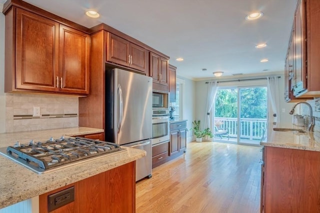 29 Carlton St Unit 2, Salem, MA 01970 - kitchen with stainless steel appliances, light stone countertops, light wood finished floors, brown cabinets, and tasteful backsplash