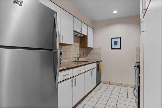 kitchen with a sink, tasteful backsplash, light tile patterned floors, white cabinets, and appliances with stainless steel finishes