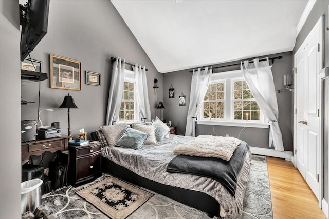 bedroom with lofted ceiling, multiple windows, and light hardwood / wood-style flooring