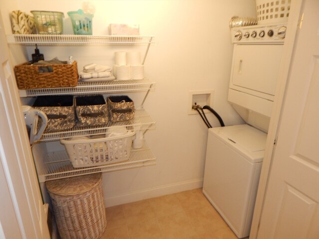 clothes washing area with light tile patterned floors and stacked washer and dryer