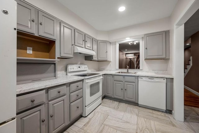 kitchen featuring white appliances, sink, gray cabinets, light wood-type flooring, and light stone counters