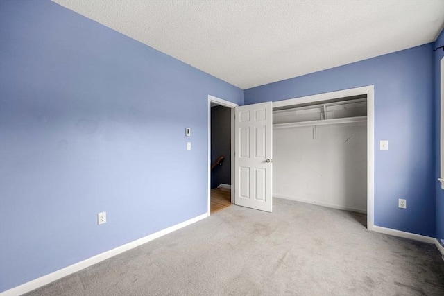 unfurnished bedroom featuring light carpet, a closet, and a textured ceiling