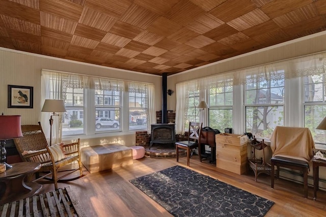 sitting room featuring a wood stove, crown molding, and wood finished floors