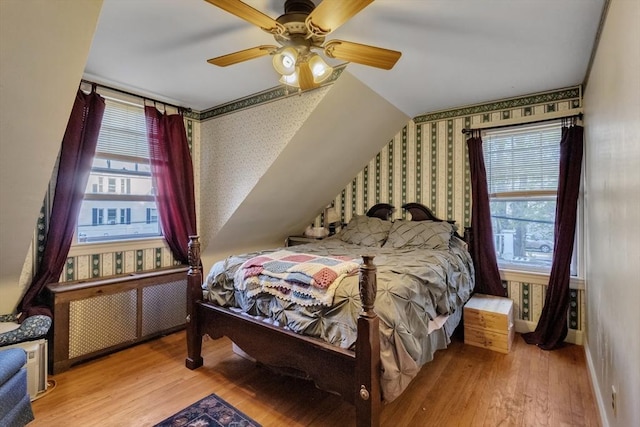 bedroom featuring multiple windows, wallpapered walls, and wood finished floors