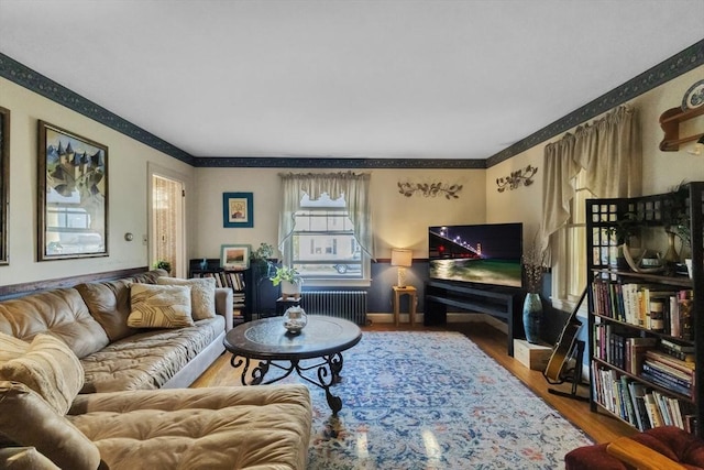 living area with radiator, crown molding, and wood finished floors
