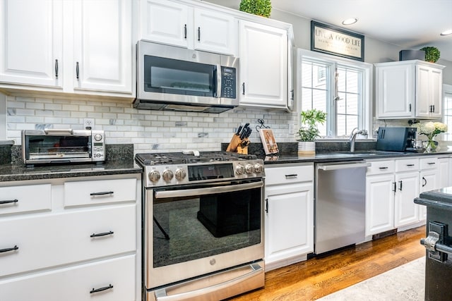 kitchen featuring light hardwood / wood-style floors, decorative backsplash, white cabinetry, and stainless steel appliances