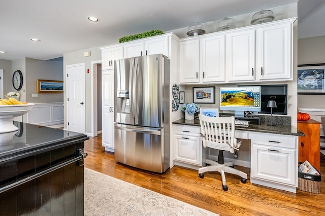 kitchen with light hardwood / wood-style floors, stainless steel fridge, white cabinets, and built in desk