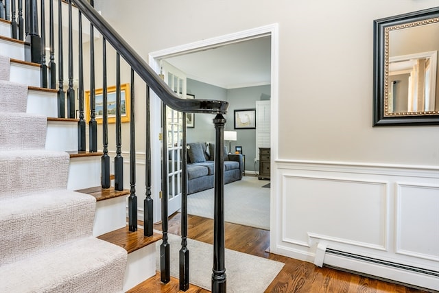 stairs featuring a baseboard radiator, crown molding, and hardwood / wood-style flooring