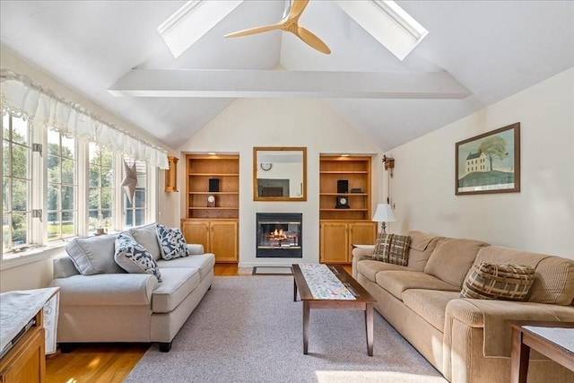 49 Karen Rd, Hanover, MA 02339 - living area featuring a skylight, light wood-type flooring, vaulted ceiling, built in shelves, and a glass covered fireplace