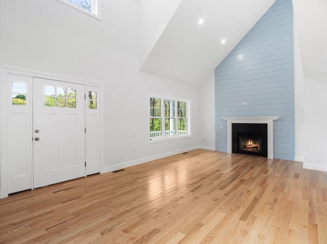 316 Old Westport Rd, Dartmouth, MA 02747 - unfurnished living room with high vaulted ceiling, light wood-style floors, baseboards, and a warm lit fireplace