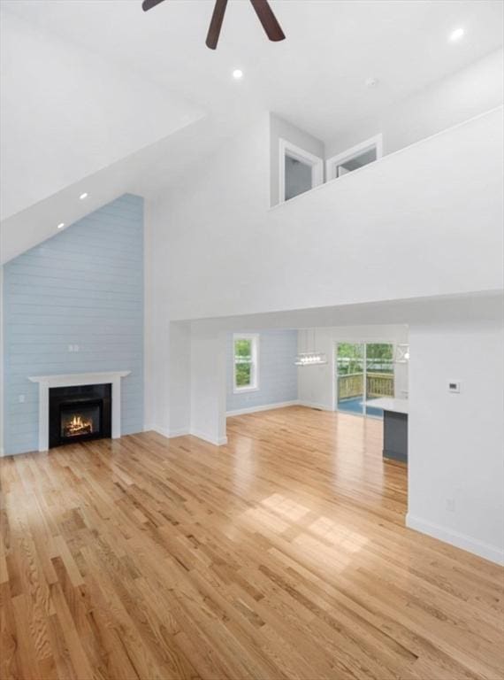316 Old Westport Rd, Dartmouth, MA 02747 - unfurnished living room featuring a high ceiling, ceiling fan, a lit fireplace, baseboards, and wood finished floors