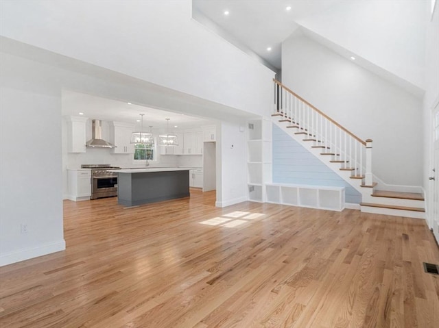 316 Old Westport Rd, Dartmouth, MA 02747 - unfurnished living room featuring stairs, light wood-style floors, a high ceiling, a sink, and baseboards