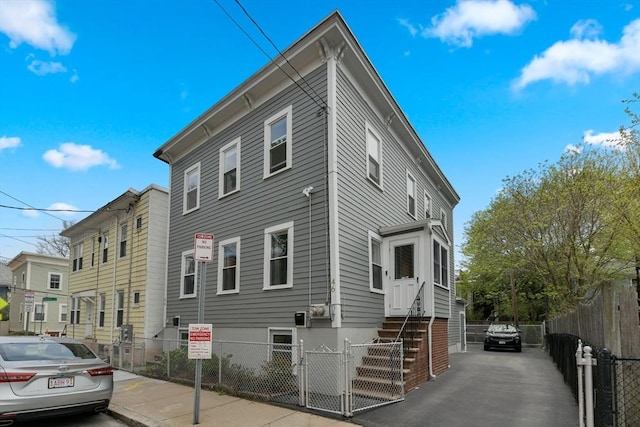 view of side of home featuring a fenced front yard and a gate