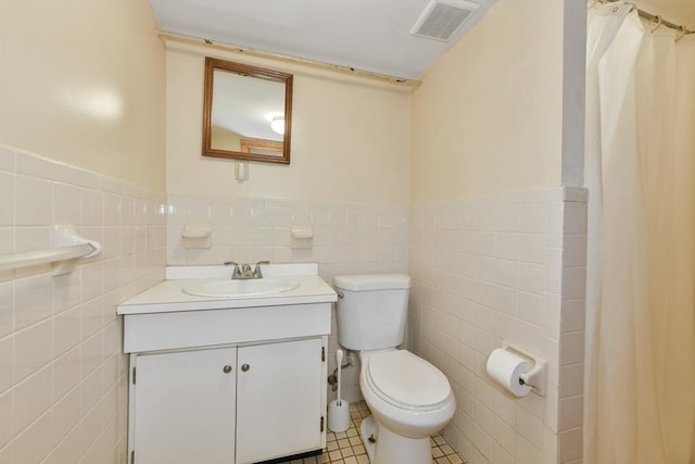 full bathroom with tile walls, toilet, vanity, wainscoting, and a shower with curtain