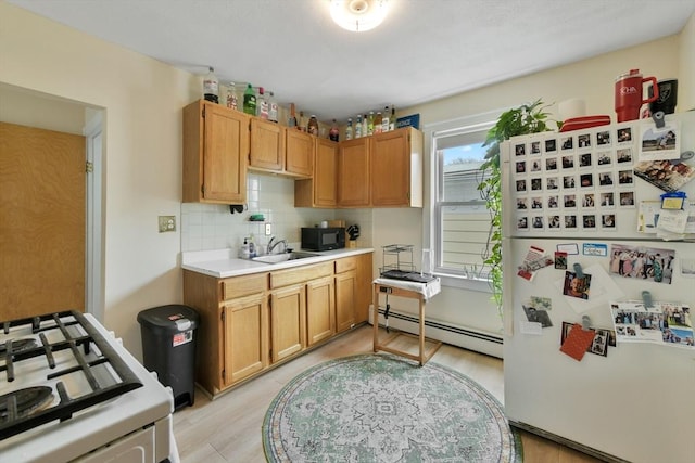 kitchen featuring white appliances, a baseboard radiator, a sink, light wood-type flooring, and light countertops