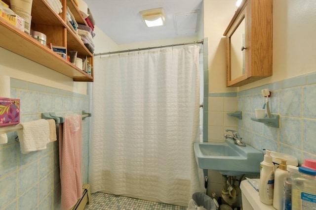 bathroom with tile walls, a sink, wainscoting, a shower with curtain, and tile patterned flooring