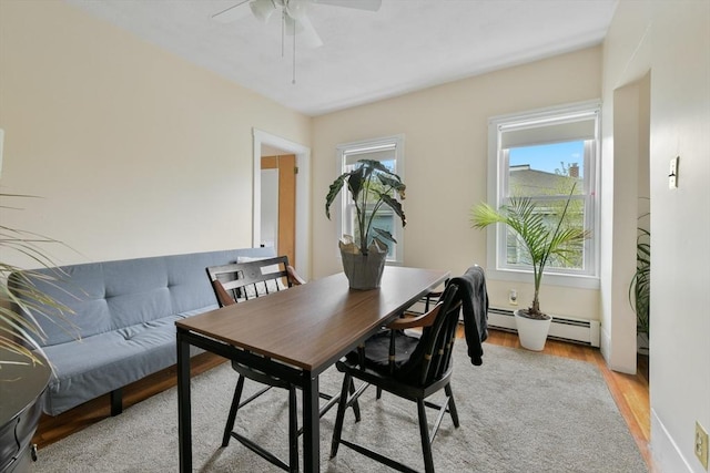 office area with a baseboard radiator, ceiling fan, and light wood-style floors