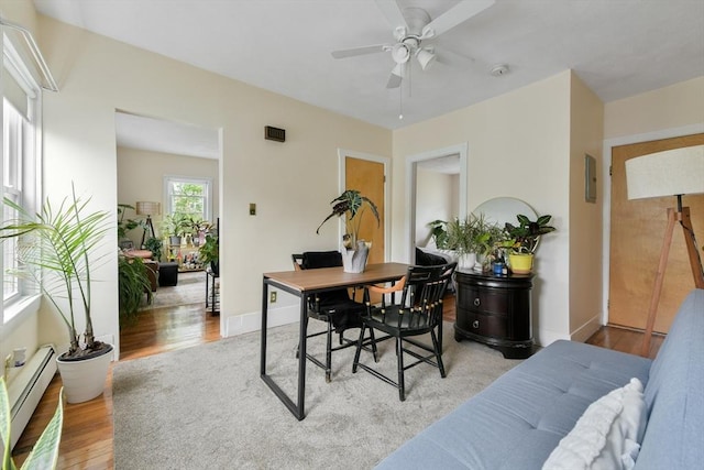office area featuring a baseboard radiator, light wood-style flooring, ceiling fan, and baseboards