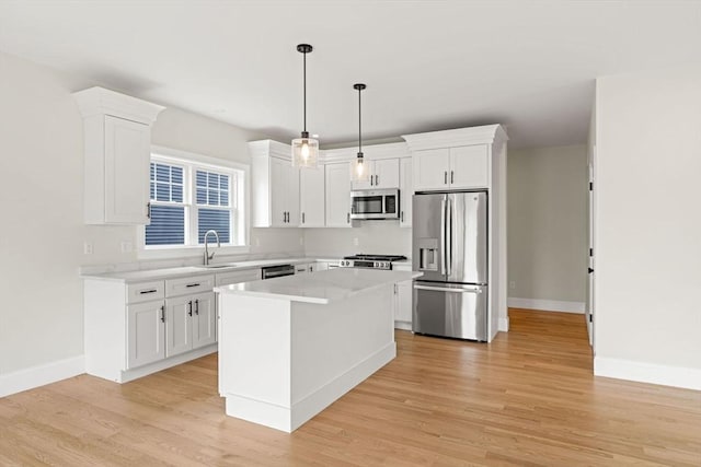 kitchen featuring a sink, light countertops, light wood-style flooring, stainless steel appliances, and white cabinetry