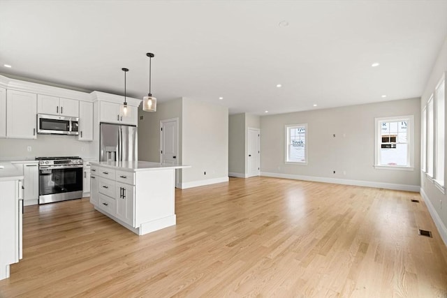 kitchen with a kitchen island, stainless steel appliances, white cabinetry, and light countertops