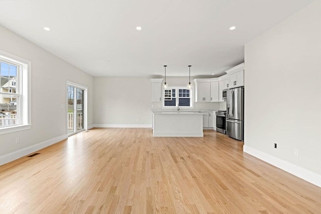 unfurnished living room featuring baseboards, recessed lighting, and light wood finished floors