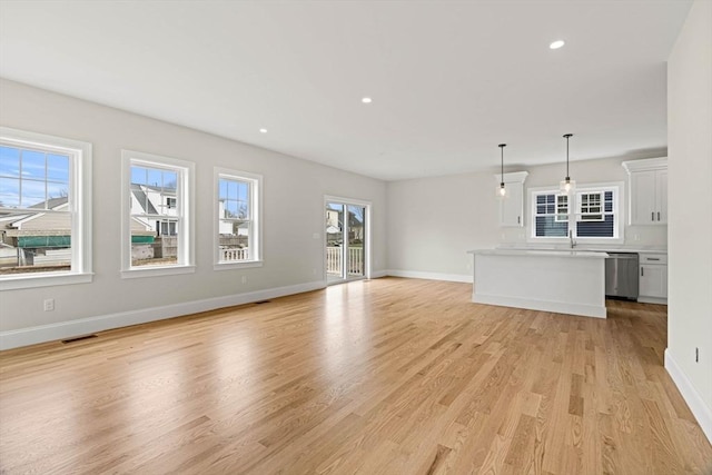unfurnished living room with plenty of natural light, recessed lighting, baseboards, and light wood finished floors