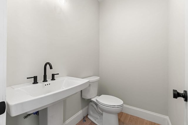 bathroom with a sink, baseboards, toilet, and wood finished floors