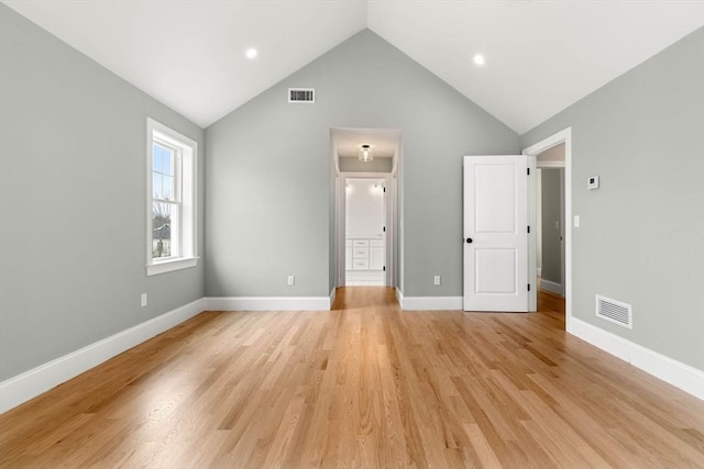 unfurnished bedroom with baseboards, vaulted ceiling, light wood finished floors, and visible vents