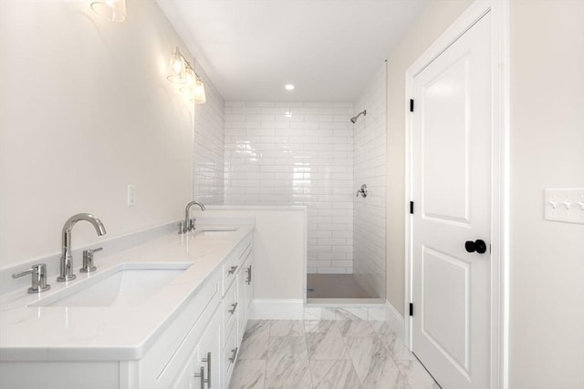 bathroom with double vanity, tiled shower, a sink, and marble finish floor