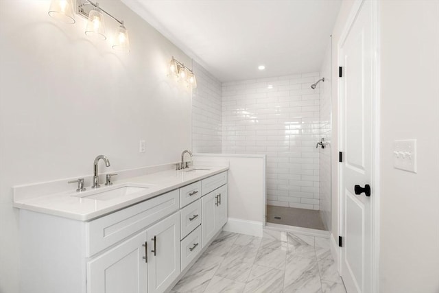 full bath featuring double vanity, tiled shower, a sink, and marble finish floor