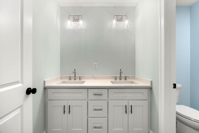 bathroom featuring double vanity, toilet, and a sink