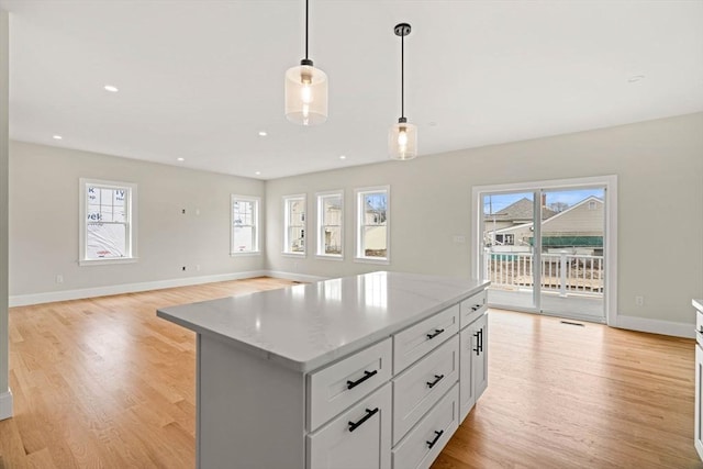 kitchen featuring light wood-style floors, pendant lighting, a kitchen island, and a wealth of natural light