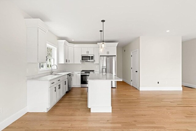 kitchen with appliances with stainless steel finishes, a sink, light countertops, white cabinetry, and baseboards