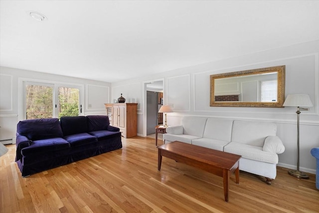 living area featuring light wood-style floors, a baseboard heating unit, and a decorative wall