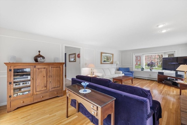 living room featuring a baseboard radiator, a decorative wall, and light wood-style flooring