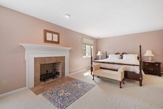 bedroom with light colored carpet, a baseboard heating unit, baseboards, and a tiled fireplace