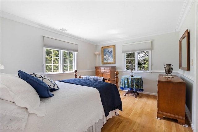 bedroom with crown molding, baseboards, visible vents, and light wood finished floors