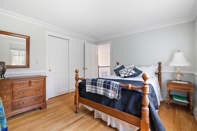 bedroom featuring light wood-style floors, crown molding, and a closet