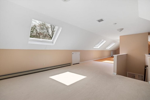 additional living space with visible vents, baseboard heating, carpet, and vaulted ceiling with skylight